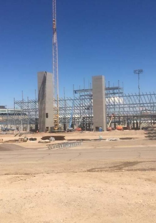 Construction site with steel framework and concrete pillars under clear sky.