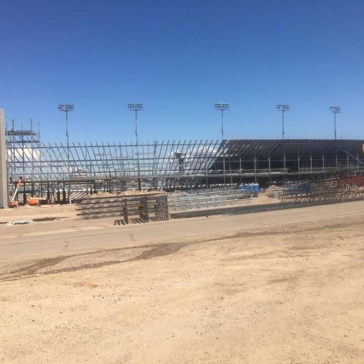 Construction site with steel framework and building materials under clear blue sky.